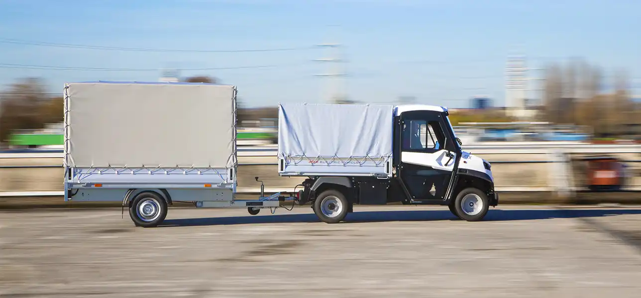 Electric commercial vehicle with tarpaulin cover and towing trailer